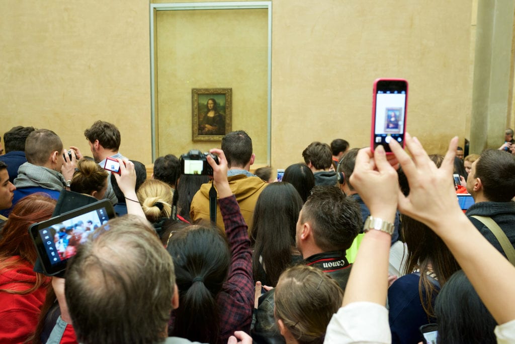 Tourists photographing the famous picture of Mona Lisa in Louvre Museum.