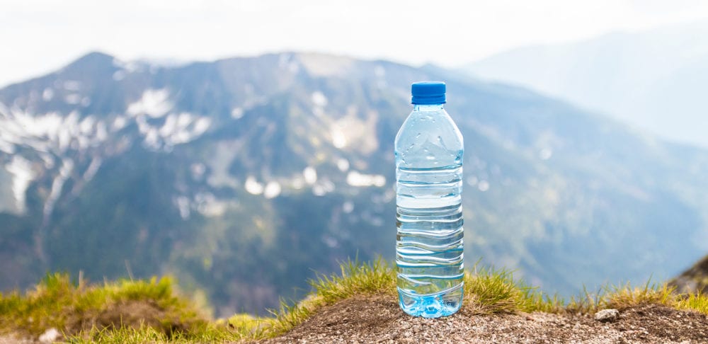 Water in plastic bottles on the stone against the background of a picturesque view of mountains.