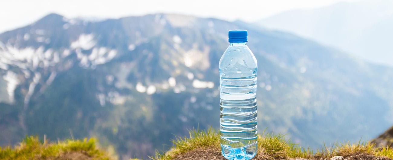 Water in plastic bottles on the stone against the background of a picturesque view of mountains.