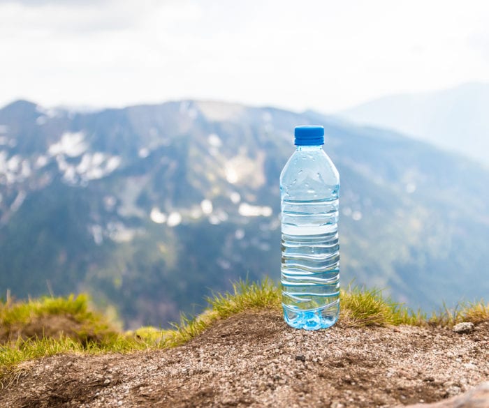 Water in plastic bottles on the stone against the background of a picturesque view of mountains.