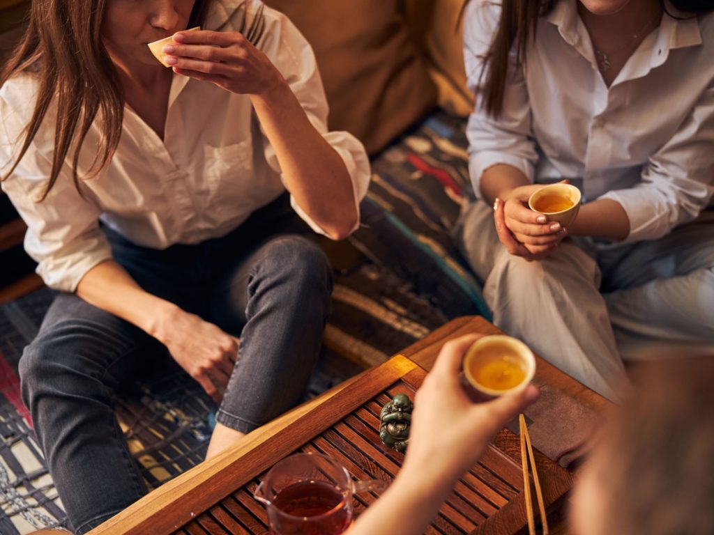 Women seated on the floor drinking tea