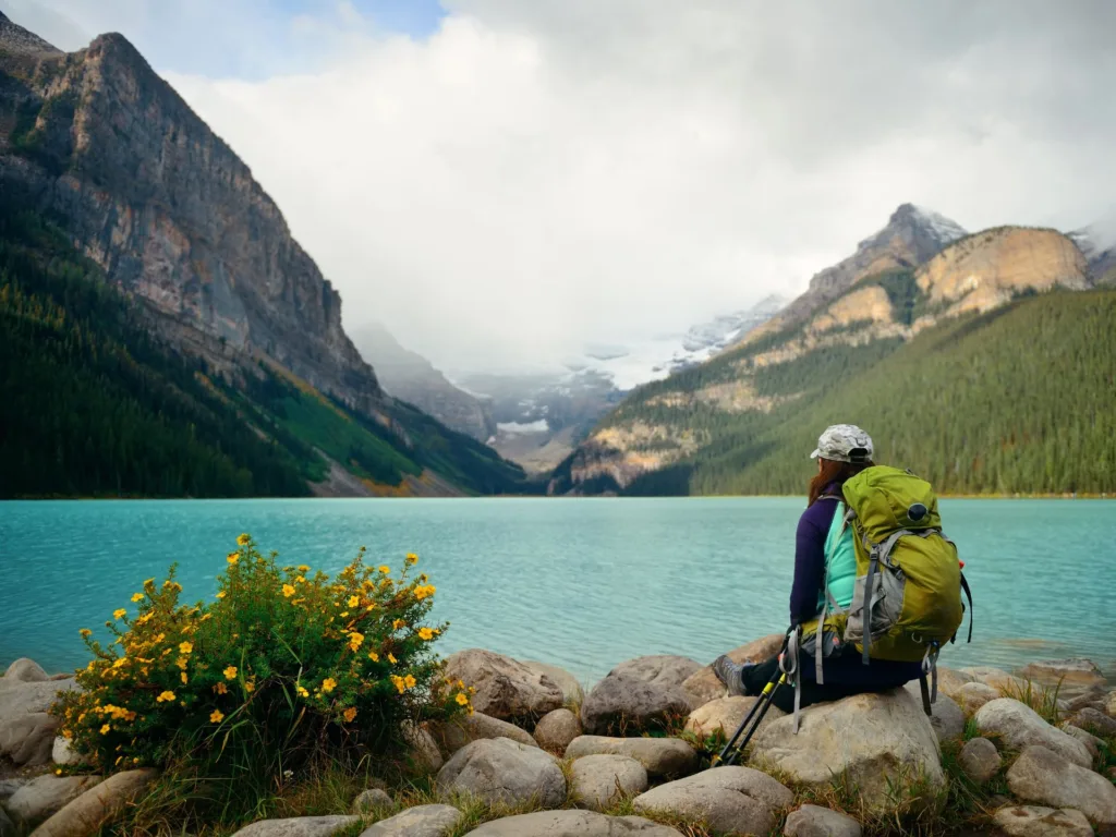 A hiker rests on a rock overlooking Lake Louise in Banff National Park. 