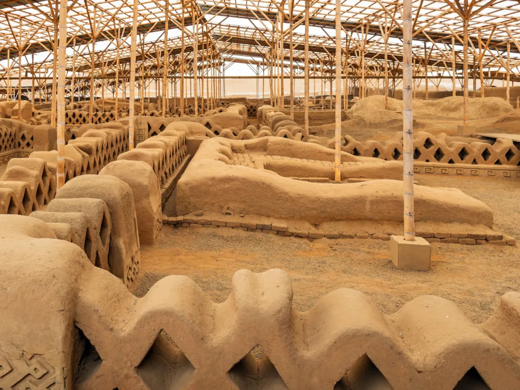 Adobe archaeological pieces under a protective canopy at Chan Chan, Peru.