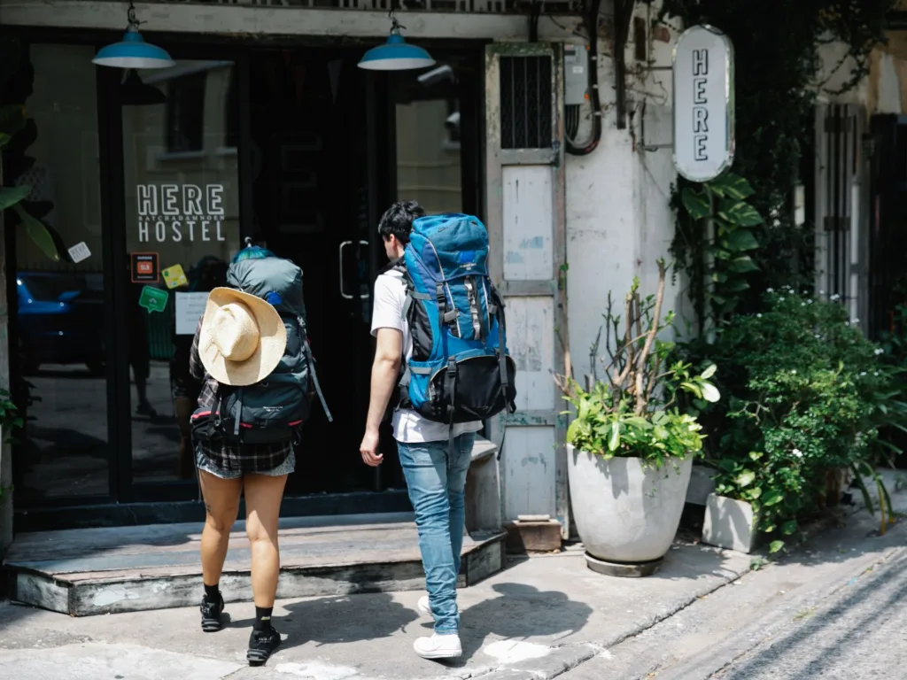Couple with backpacks entering a hostel