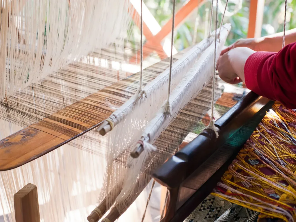 Woman weaving silk in traditional way at manual loom in Laos. 